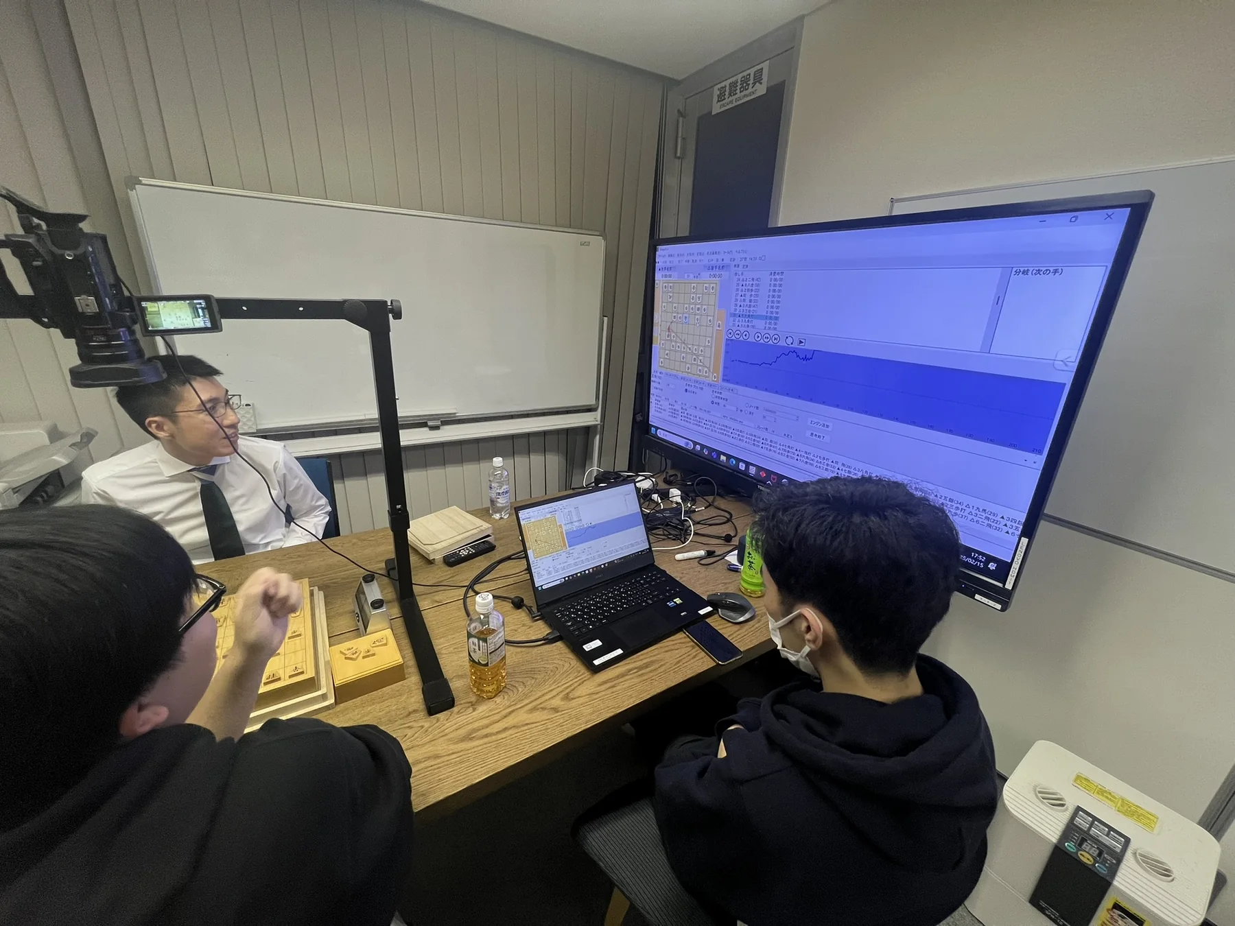 高野智史六段と参加者が大型モニターで棋譜分析を行う様子