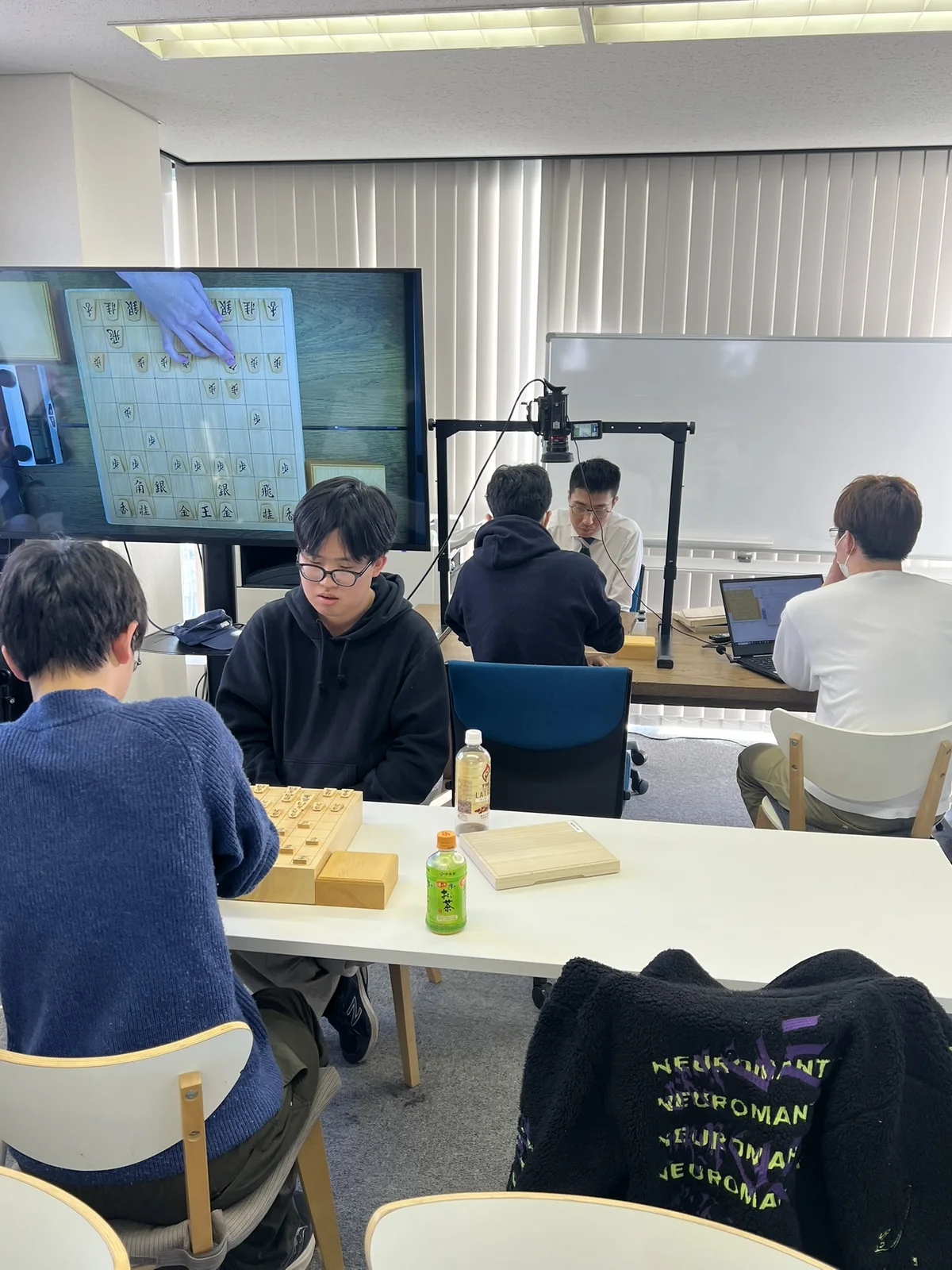 参加者が将棋盤と大型モニターを使って研究する様子